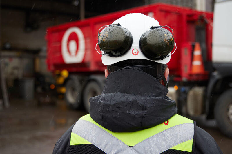 Veolia Employee stands in front of waste transporter