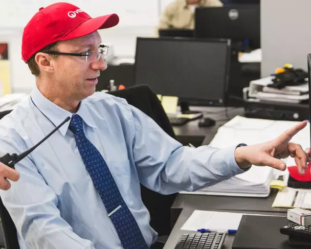 Veolia Mitarbeiter sitzt vor dem PC und zeigt etwas mit seinem Finger am Bildschirm